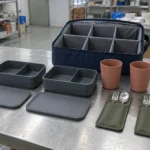 Two-person portable tableware sample set arranged beside partitioned carry case — AI-generated conceptual illustration