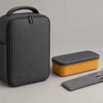 Closed graphite driver bento case beside amber box and stainless cutlery sleeve