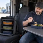 Professional driver using a navy bento box inside a parked truck cab