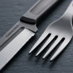Macro detail of pure titanium serrated knife and fork with laser annealed logo